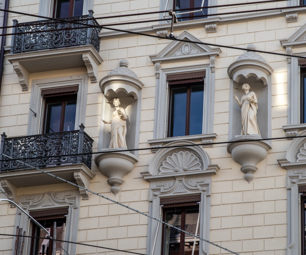 Two alcoves on each sides of a window, with draped women statues